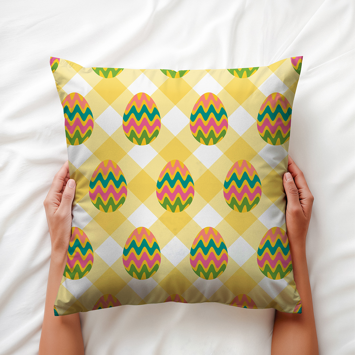 widok poduszki trzymanej obiema rękami na białym prześcieradle