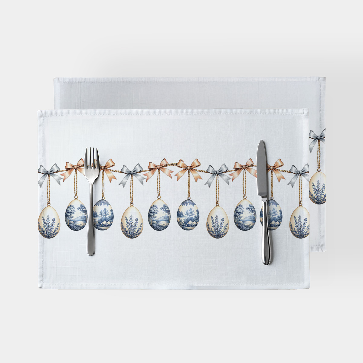 białe podkładki z motywem wiszących pisanek na kokardach, widok z góry z nakryciem