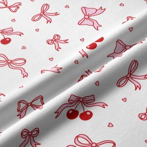 Zbliżenie na nadruk kokardek i par wisienek na białym tle, detal tkaniny