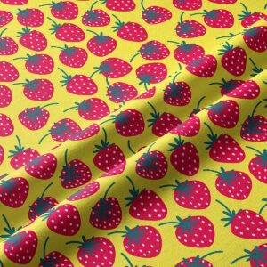 Zbliżenie na tkaninę z nadrukowanymi czerwonymi truskawkami i strukturą materiału