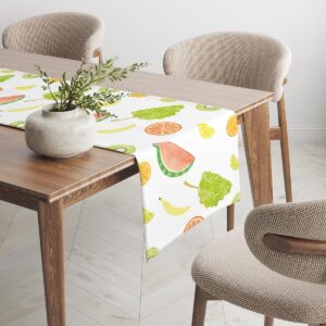 Bieżnik z motywem owoców ułożony na drewnianym stole z dekoracyjnym wazonem