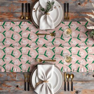 Widok z góry na nakryty stół z bieżnikiem w drobny wzór stokrotek i zastawą stołową