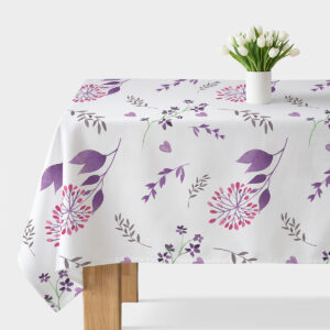 Stół nakryty obrusem z akwarelowym wzorem fioletowych gałązek i różowych kwiatów z białym wazonem z tulipanami