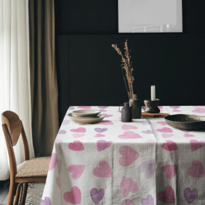 aranżacja stołu z obrusem w akwarelowe serca na tle ciemnej ściany z dekoracjami stołowymi