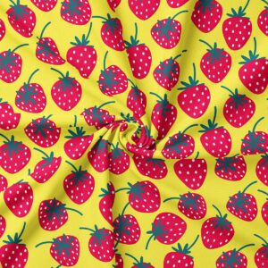Zbliżenie na materiał z nadrukiem truskawek, detal tkaniny i kolorów