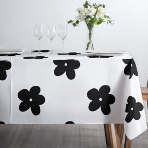 stół zastawiony kieliszkami i bukietem na obrusie z dużymi czarnymi kwiatami