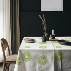 Aranżacja stołu z naczyniami na obrusie ozdobionym plasterkami kiwi