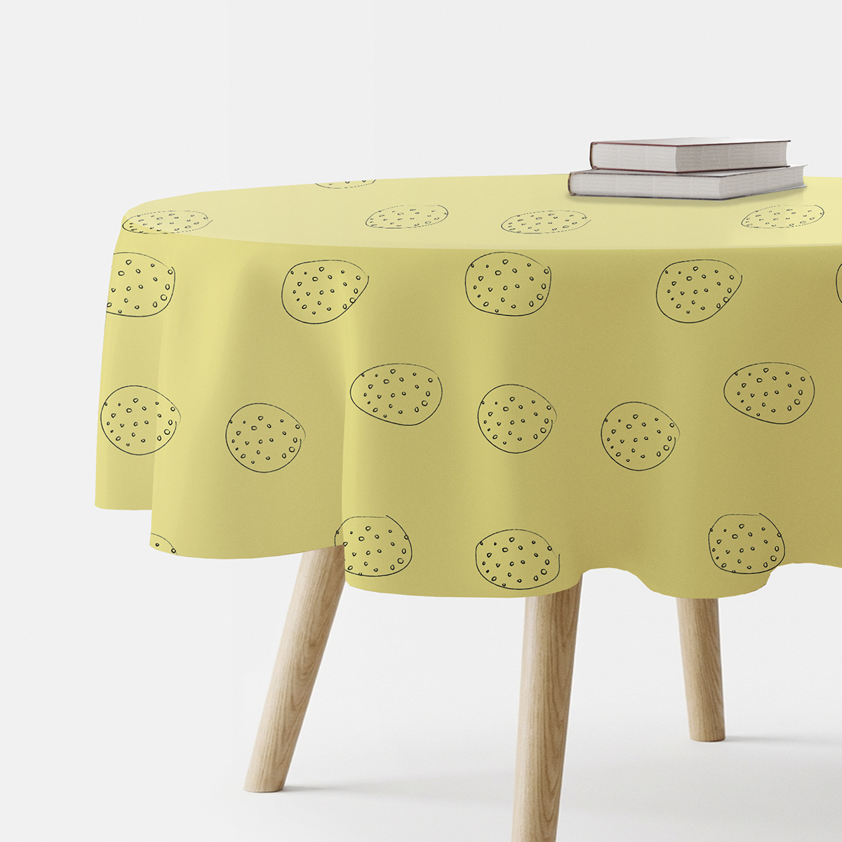 okrągły żółty obrus z ręcznie rysowanymi okręgami na stole z książkami
