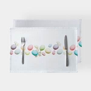 biała podkładka z poziomym pasem pastelowych pisanek i sztućcami ułożonymi na stole