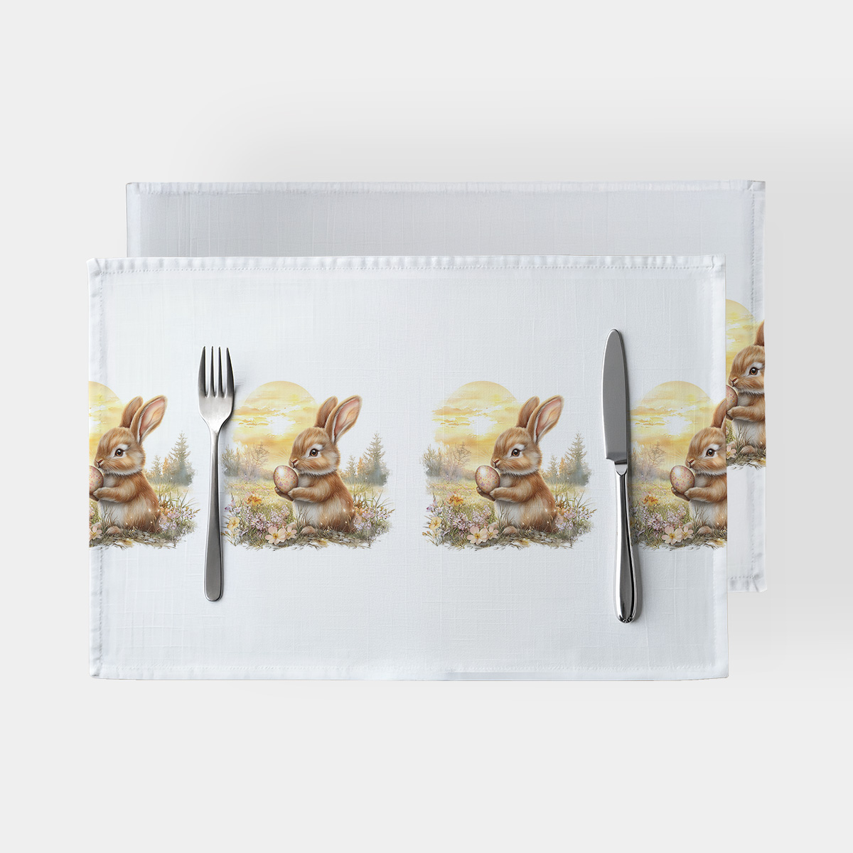 Główne ujęcie białych podkładek z powtarzającym się motywem zajączka trzymającego pisankę na kwiatowej łące