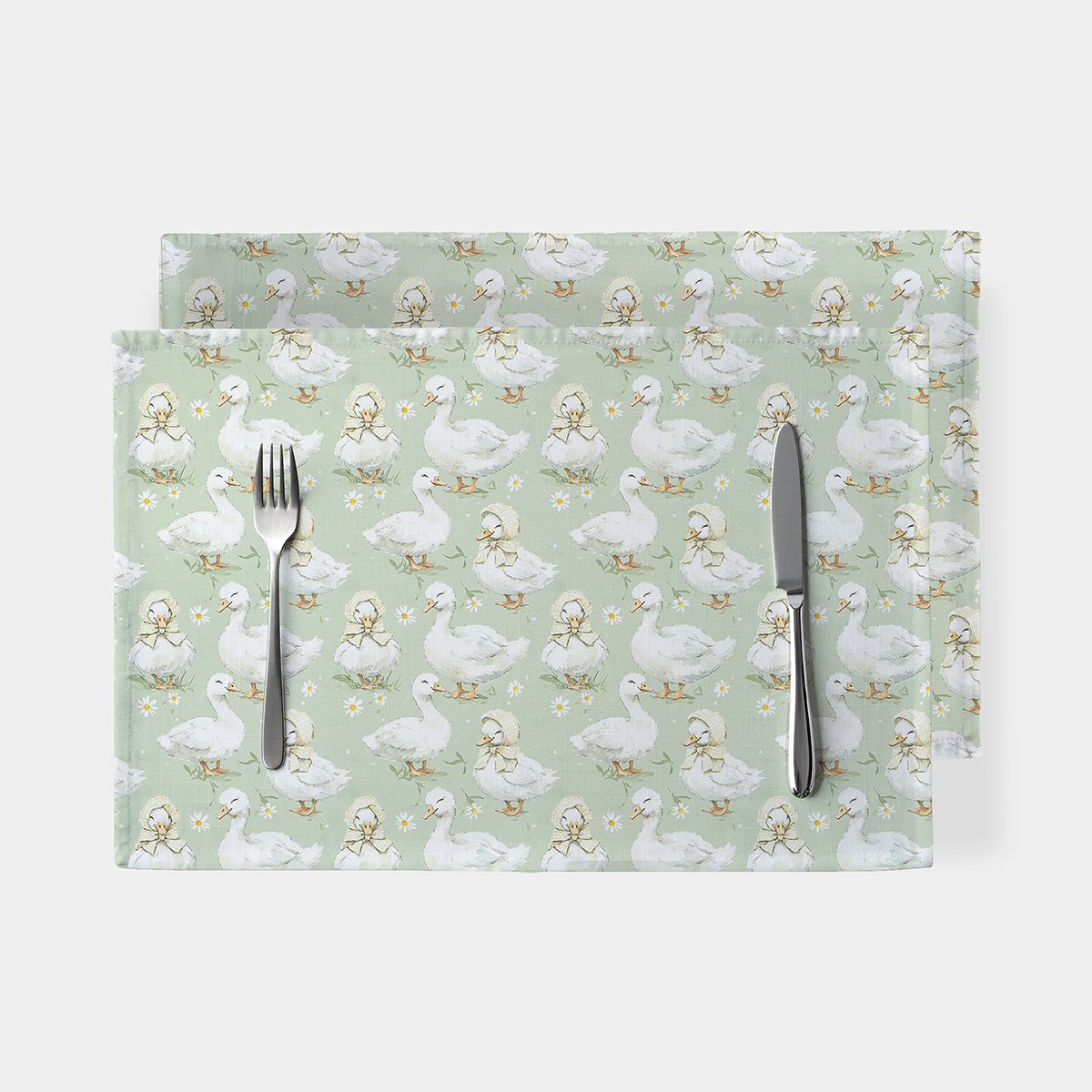 główne ujęcie podkładek z białymi kaczuszkami na miętowym tle z widocznym sztućcem