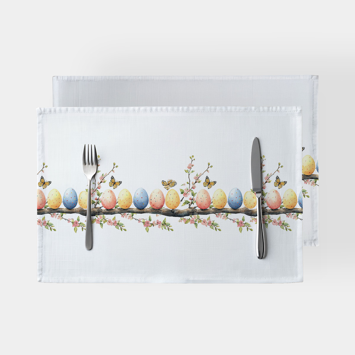 biała podkładka z poziomym pasem akwarelowych pisanek i kwiatowych gałązek, widok z góry