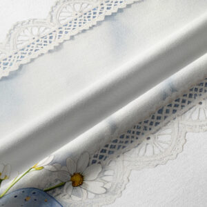 Zbliżenie na koronkowy motyw i delikatne stokrotki na tkaninie