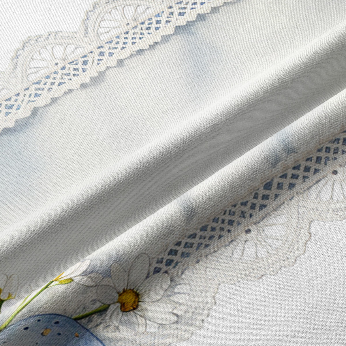 Zbliżenie na koronkowy motyw i delikatne stokrotki na tkaninie