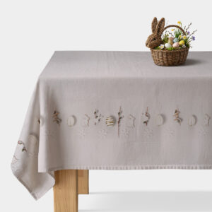 Obrus z delikatnym wzorem zajączków i pisanek na stole z koszykiem z dekoracyjnymi jajkami