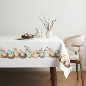 Aranżacja stołu ze świątecznymi dekoracjami: koszyk z pisankami i gałązki w tle