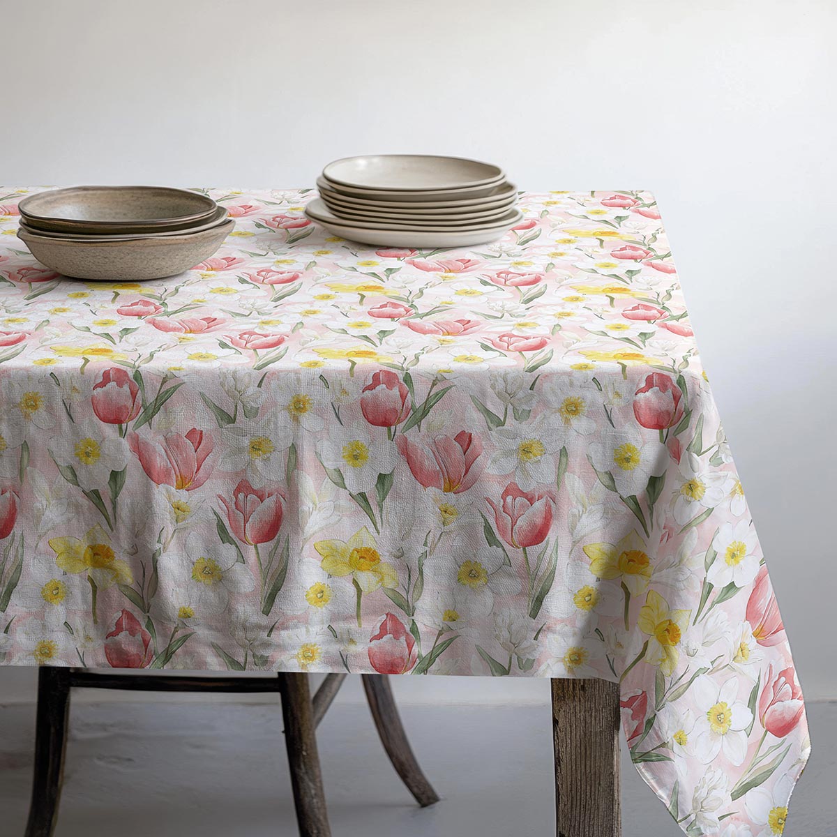 Stół nakryty obrusem z talerzami i miseczkami w neutralnych odcieniach