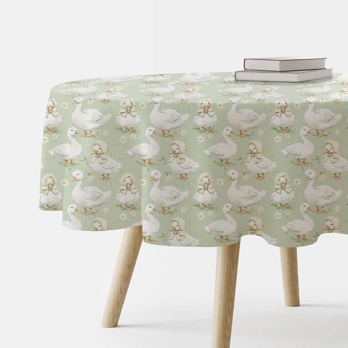 okrągły obrus z motywem białych kaczuszek na miętowym tle ułożony na stole