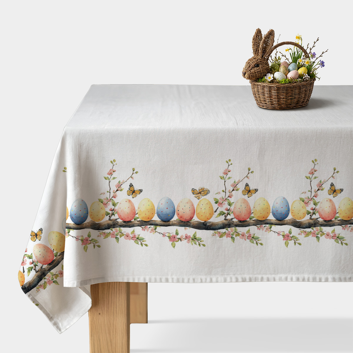 Obrus na stole z pasem malowanych pisanek, kwiatów i motyli na białym tle