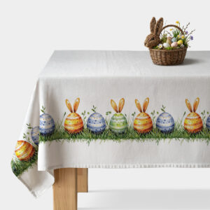 Obraz główny: biały obrus z rysunkowym paskiem kolorowych jajek z króliczymi uszami i trawą biegnącym wzdłuż krawędzi stołu