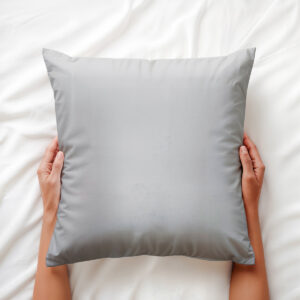 Poduszka trzymana dłońmi na łóżku, widok z góry i detal materiału