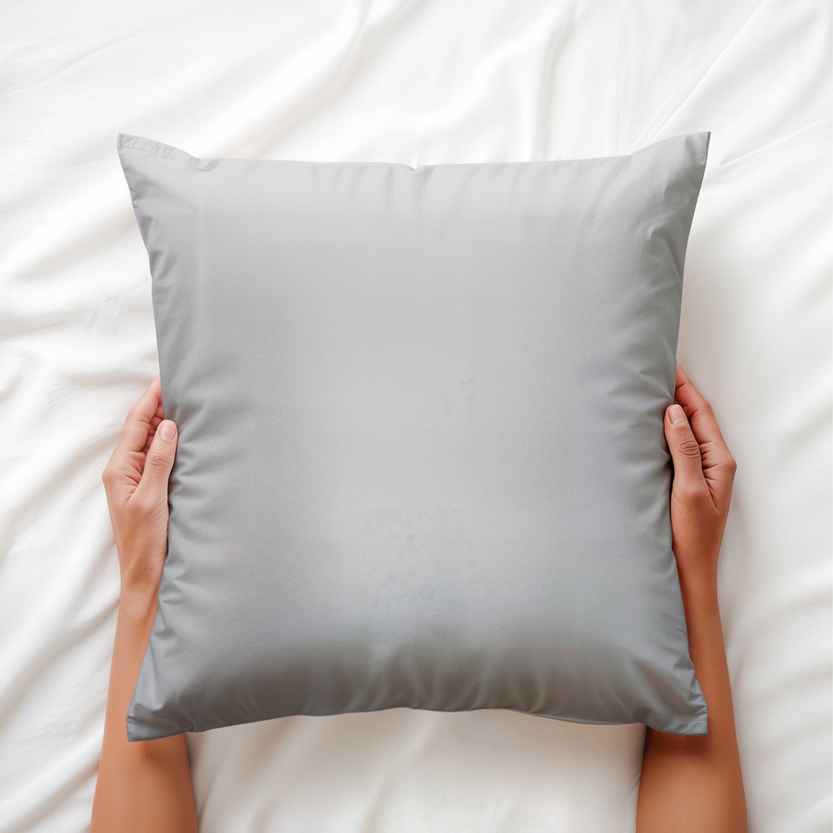 Poduszka trzymana dłońmi na łóżku, widok z góry i detal materiału