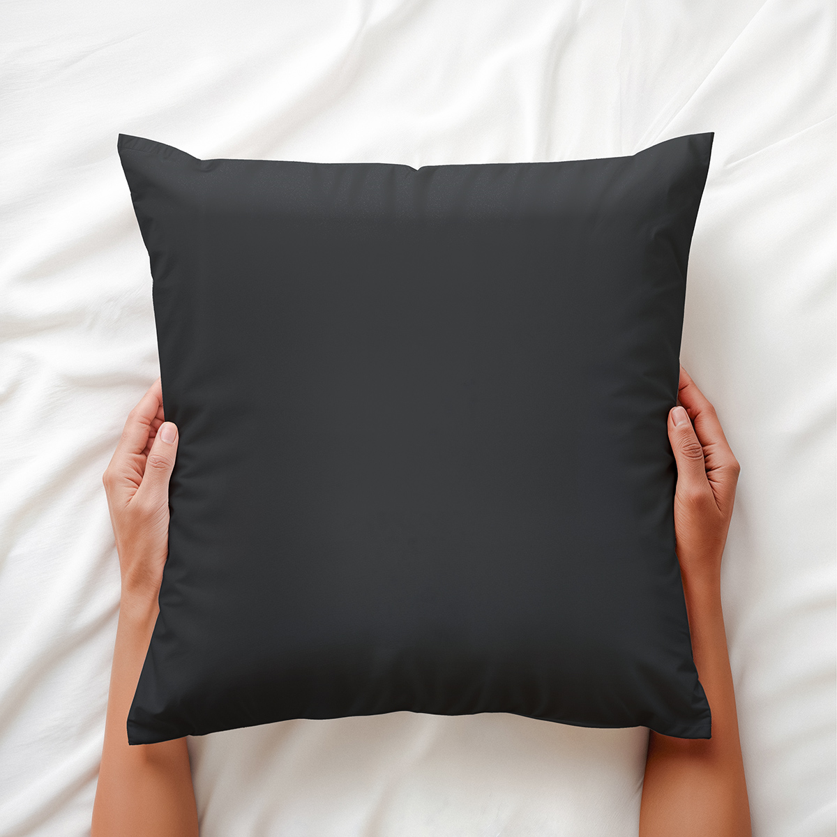 ręce trzymające grafitową poduszkę na pościeli, ujęcie aranżacyjne