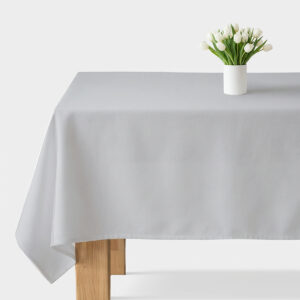 Jasnoszary obrus rozłożony na stole z białym wazonem tulipanów