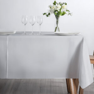 Nakrycie stołu z kieliszkami i bukietem na gładkim jasnoszarym obrusie