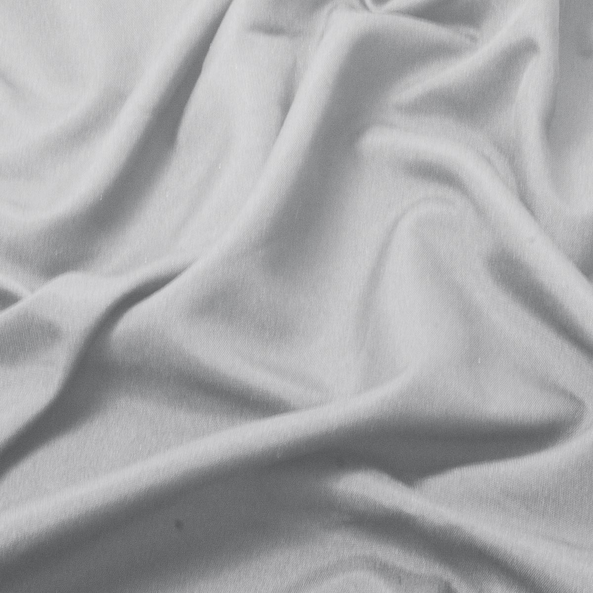 zbliżenie na gładką, lekko marszczoną fakturę jasnoszarego materiału obrusa