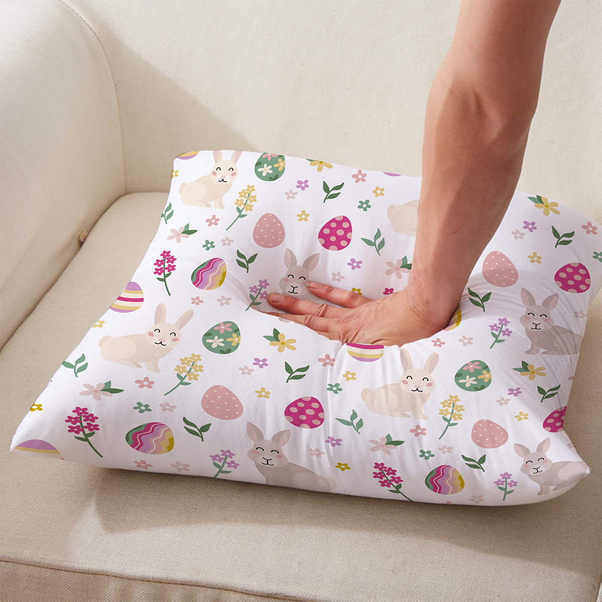 Osoba naciskająca poduszkę z wiosennym wzorem króliczków i pisanek, zbliżenie na materiał