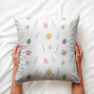 Ręce trzymające poduszkę na łóżku, widoczny subtelny motyw pisanek i kwiatków