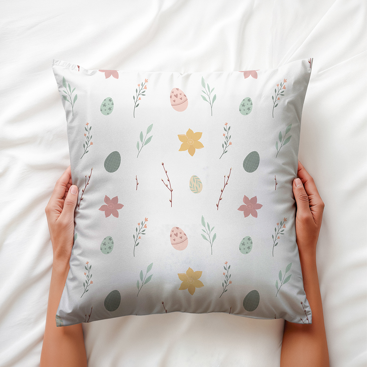 Ręce trzymające poduszkę na łóżku, widoczny subtelny motyw pisanek i kwiatków