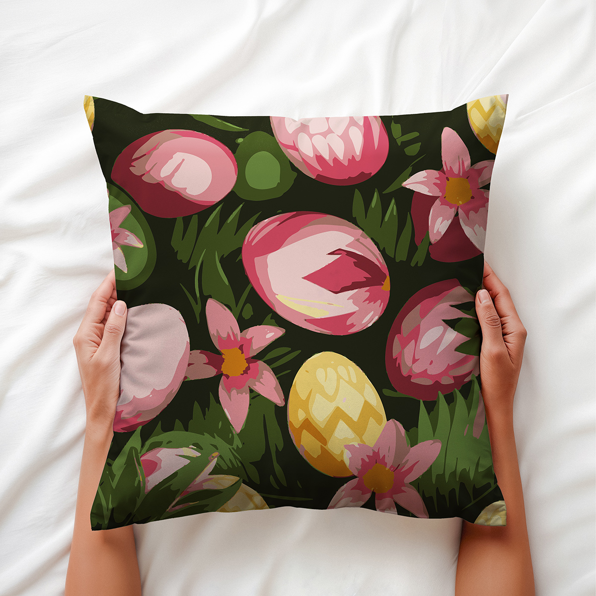 Zbliżenie na poduszkę trzymaną dłońmi na białym tle, widoczny motyw pisanek w trawie