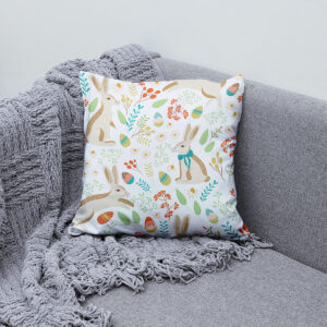 Poduszka z motywem wielkanocnym ułożona na sofie obok plecionego koca — ujęcie w aranżacji