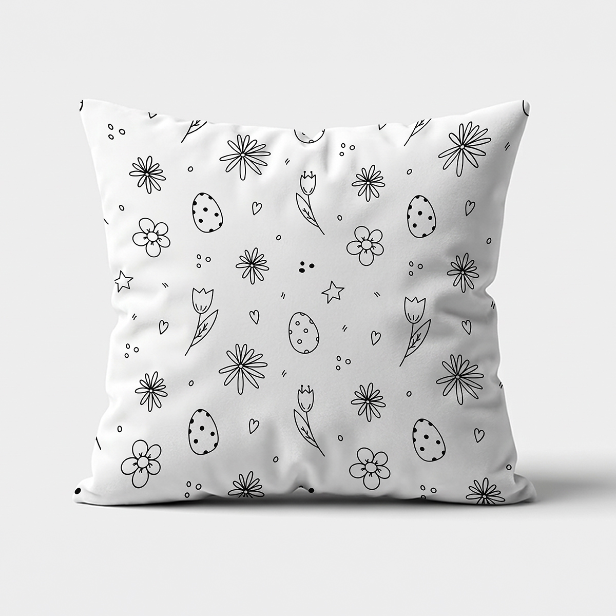 Poduszka widok z przodu z czarnym, rysunkowym wzorem jajek i kwiatów na białym tle