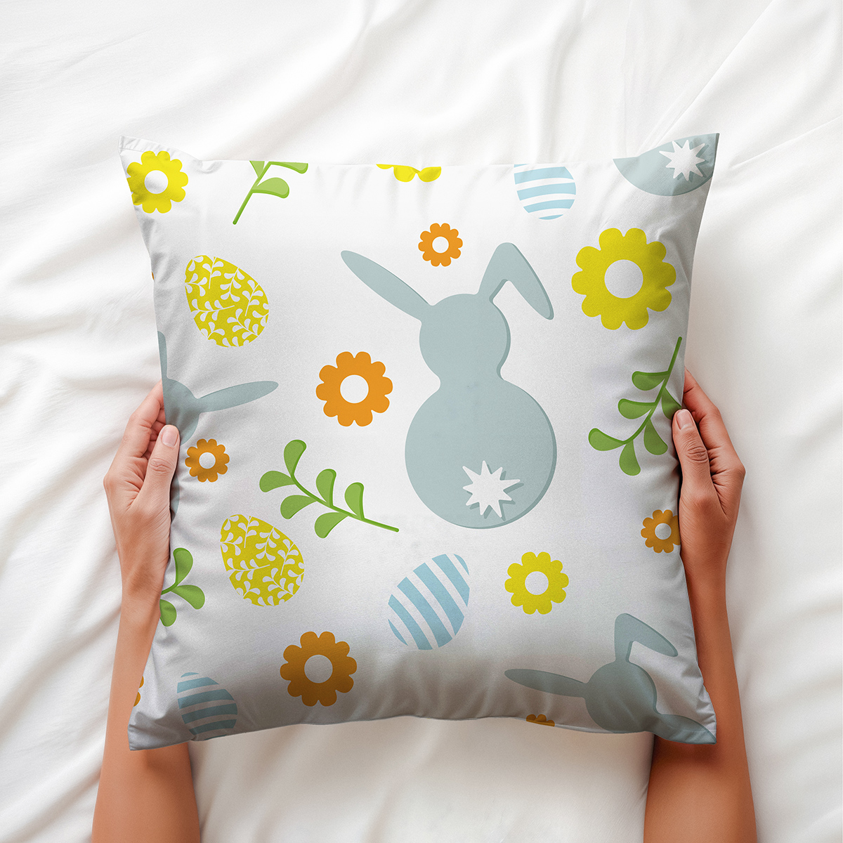 Zbliżenie na poduszkę trzymaną dłońmi, widoczny motyw zajączka i pisanek