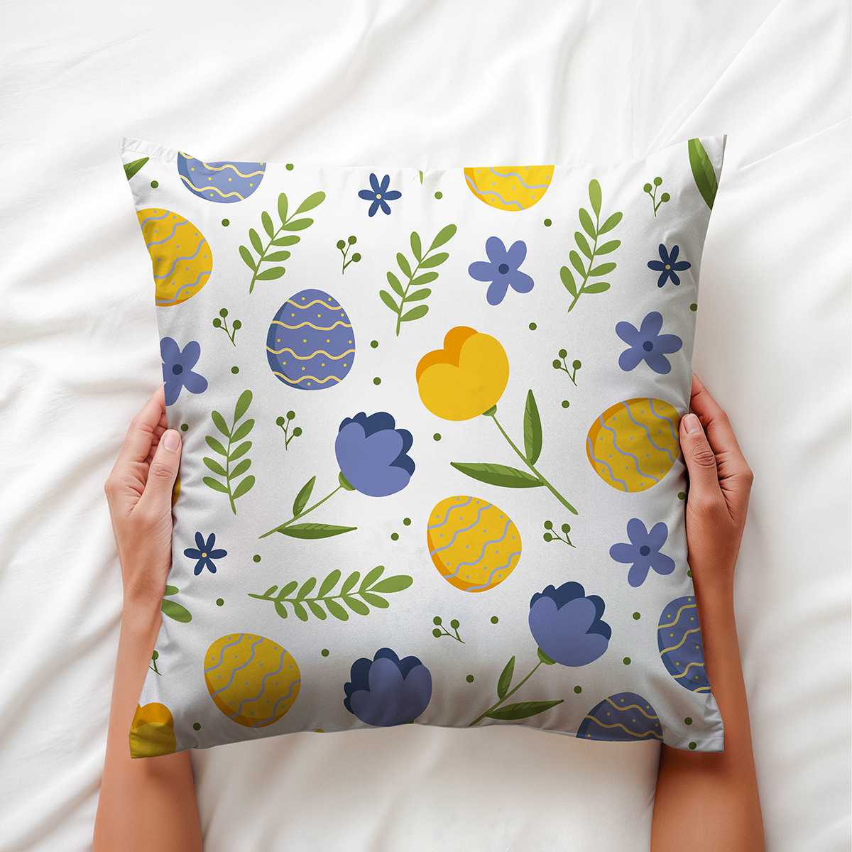ręce przytrzymujące poduszkę z motywem kolorowych pisanek i liści