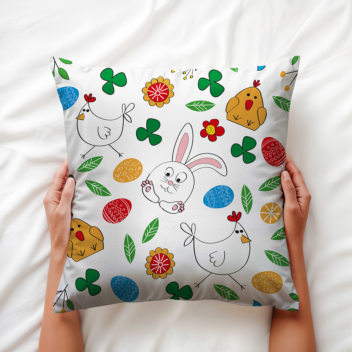 osoba trzyma poduszkę w dłoniach, widoczny kolorowy wzór z zajączkiem i pisankami