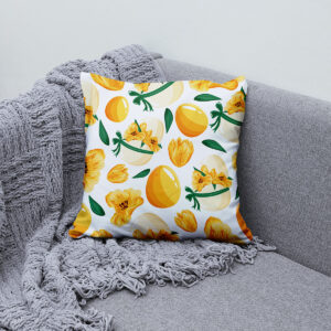 Poduszka ułożona na kanapie obok pledu, motyw żółtych kwiatów i pisanek