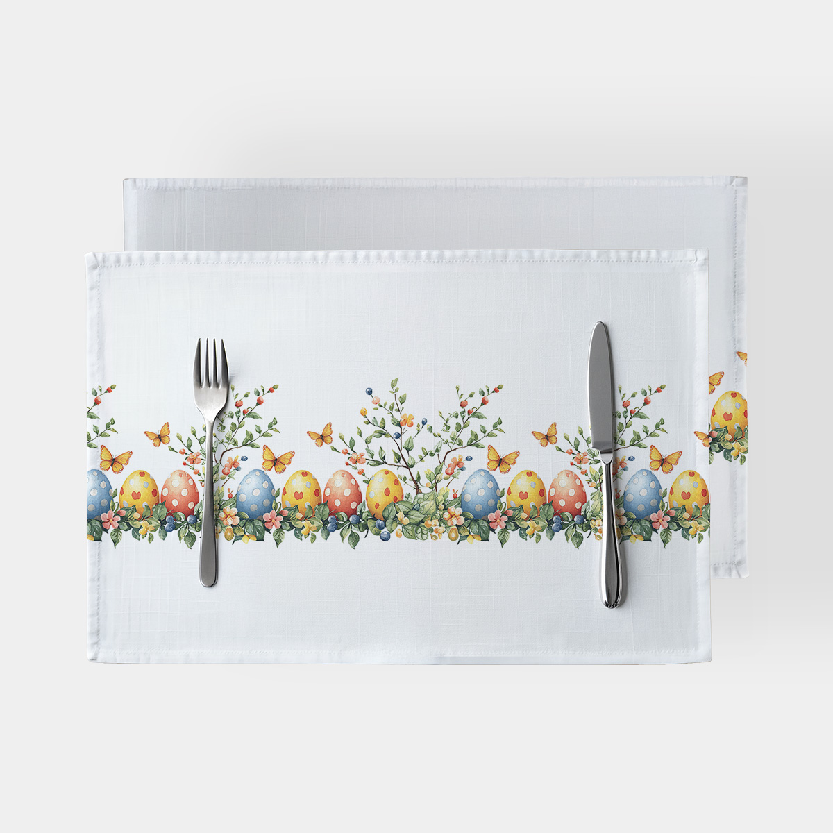 biała podkładka ze wzorem akwarelowych pisanek, gałązek i motyli, ujęcie z góry