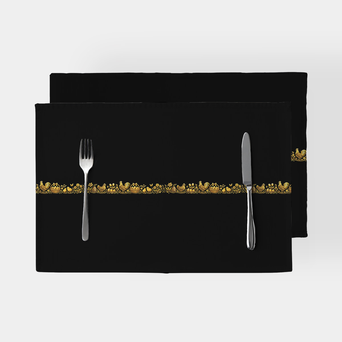 czarne podkładki z wąskim złotym ludowym pasem, ujęcie z góry ze sztućcami