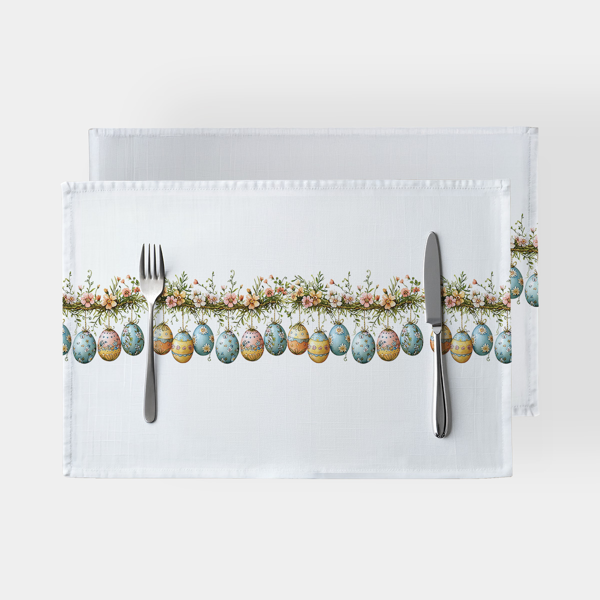 Główne ujęcie: białe podkładki z malowanymi pisankami i kwiatową girlandą na środku