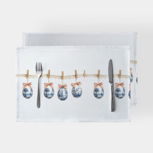 biała podkładka ze wzorem zawieszonych pisanek na koronkowym sznurku ułożona ze sztućcami