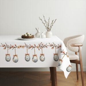 Aranżacja stołu z obrusem, naturalną dekoracją z gałązek bazi i ceramicznymi zajączkami tworząca spokojną kompozycję
