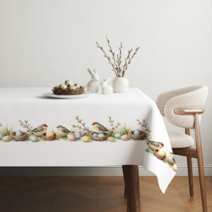 aranżacja stołu z obrusem, koszyk z jajkami i gałązkami bazi tworzą wiosenną dekorację