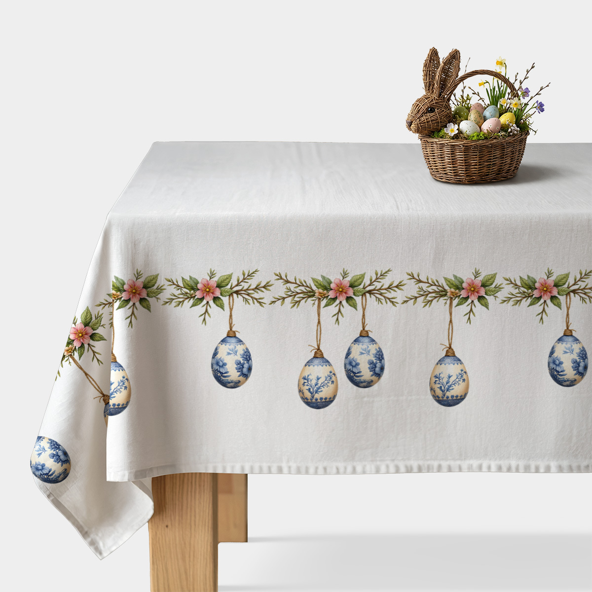 obrus z wzorem wiszących porcelanowych pisanek i gałązkami z różowymi kwiatami na białym tle