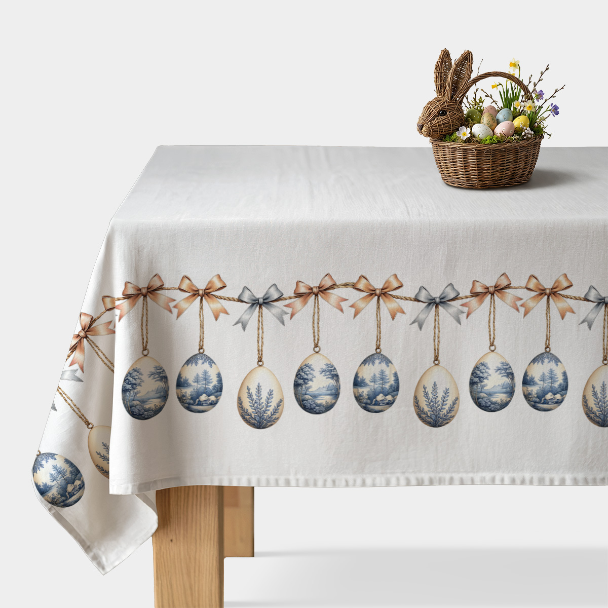 Obrus z wzorem wiszących pisanek i kokard na białym tle, widok na cały stół