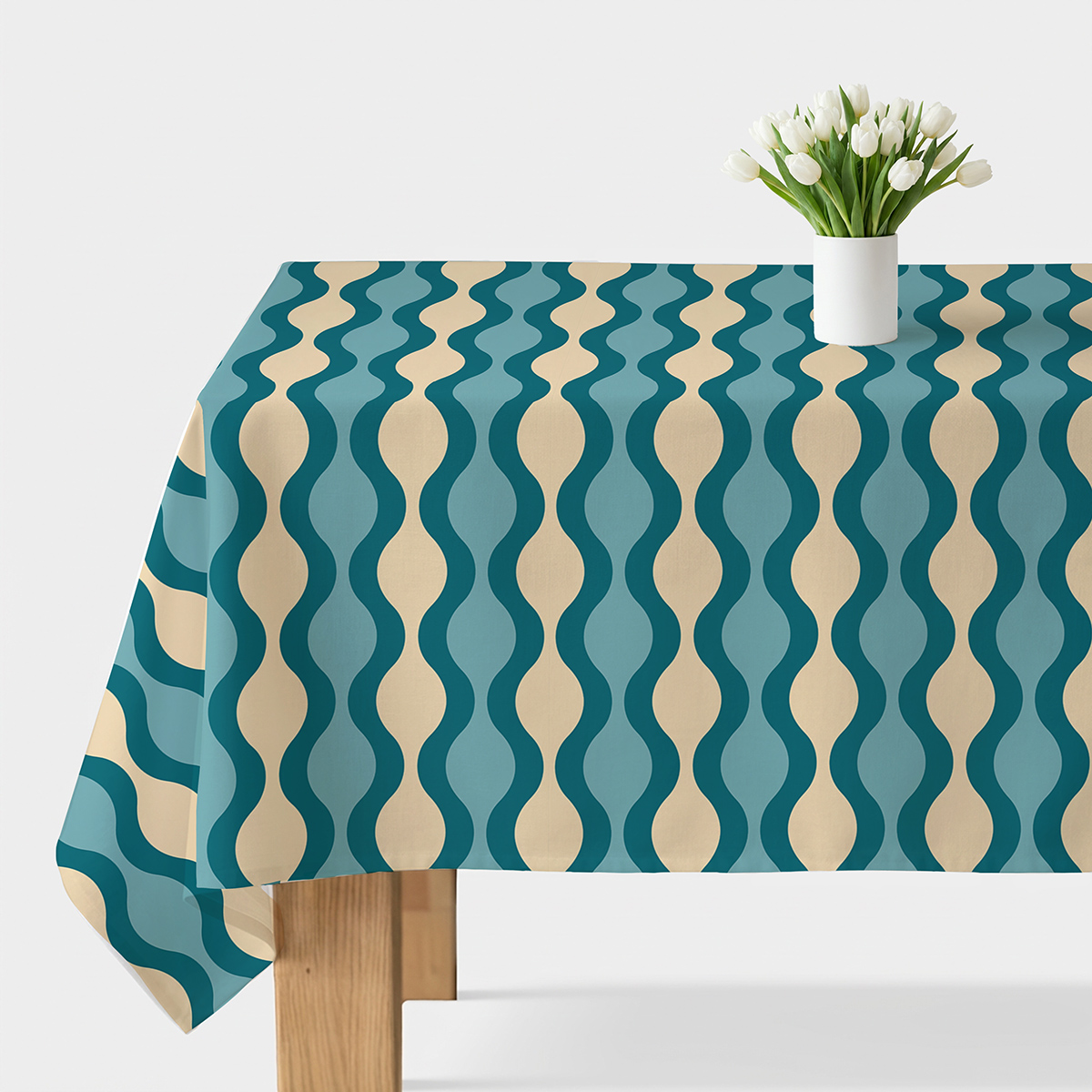 Obrus z falistym wzorem w turkusie i kremie na stole z białym wazonem i tulipanami