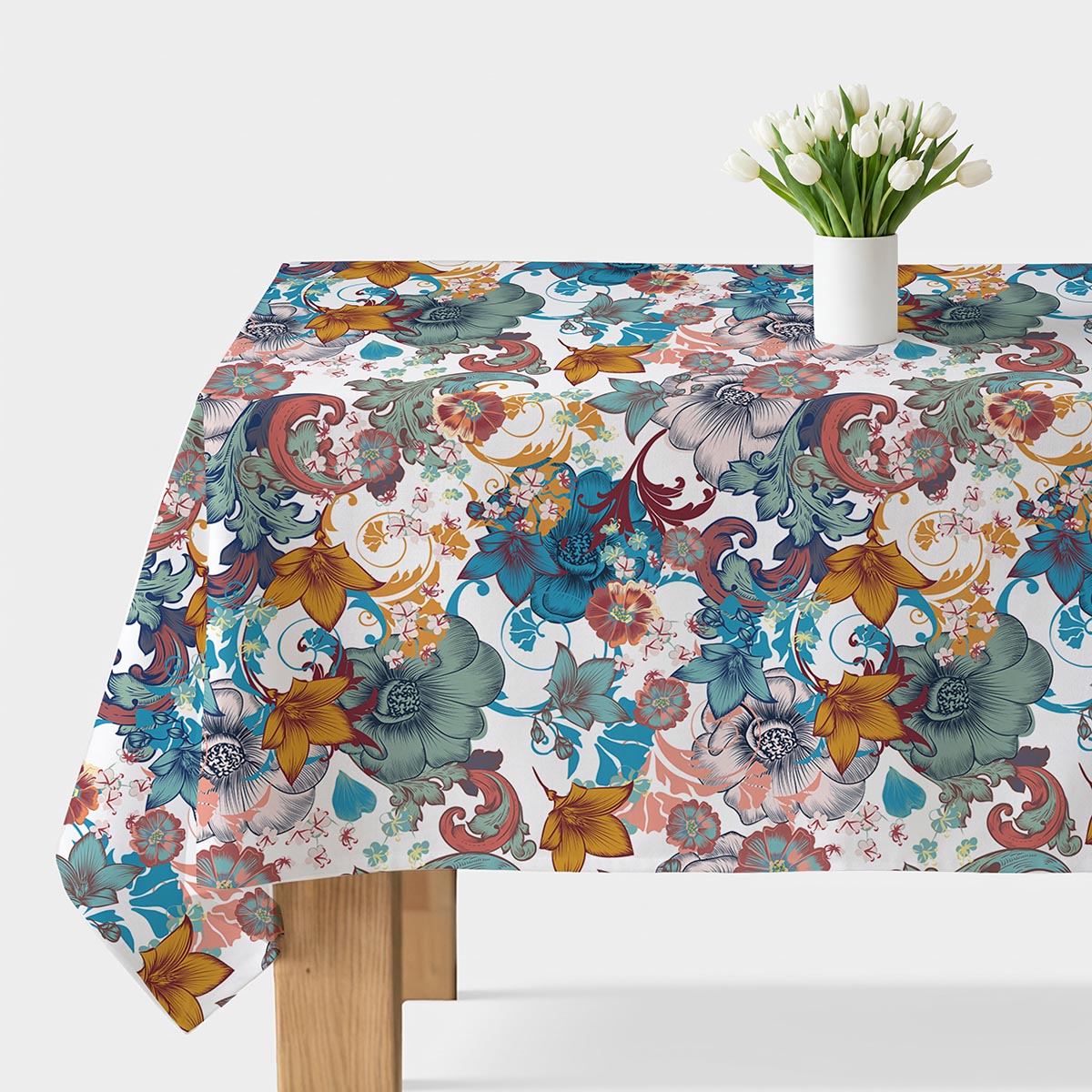 Stół nakryty obrusm w kolorowy wzór kwiatowy z wazonem białych tulipanów na środku